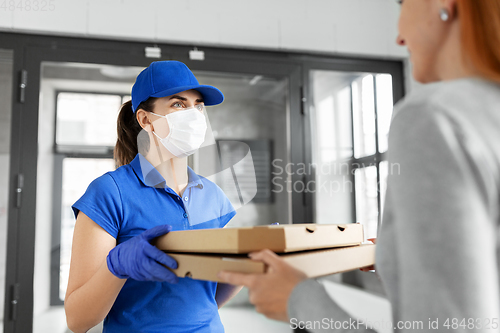 Image of delivery girl in mask giving pizza boxes to woman