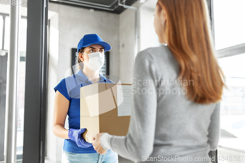 Image of delivery girl in face mask giving parcel to woman