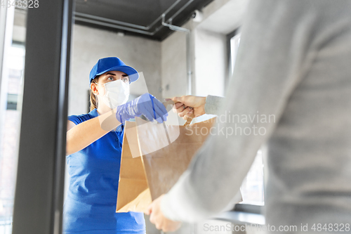 Image of delivery girl in mask giving paper bag to customer