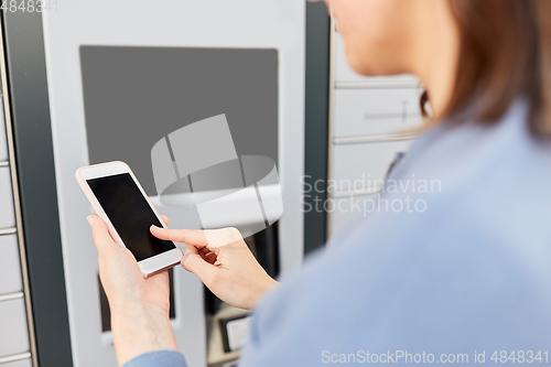 Image of woman with smartphone at automated parcel machine