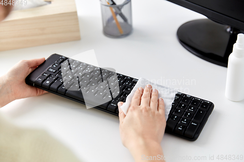 Image of close up of woman cleaning keyboard with tissue