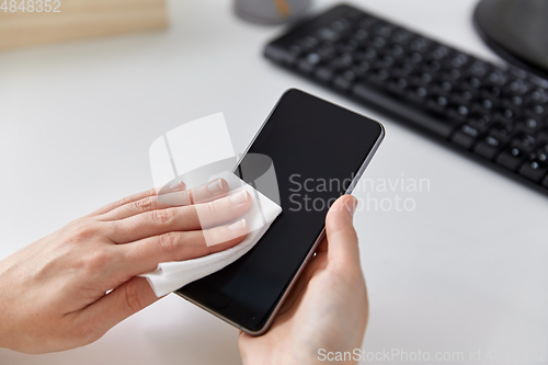 Image of close up of hands cleaning smartphone with tissue