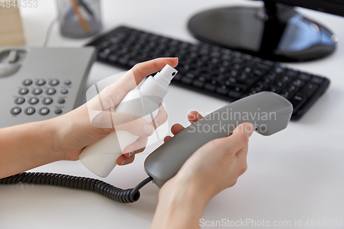 Image of close up of woman cleaning phone with sanitizer