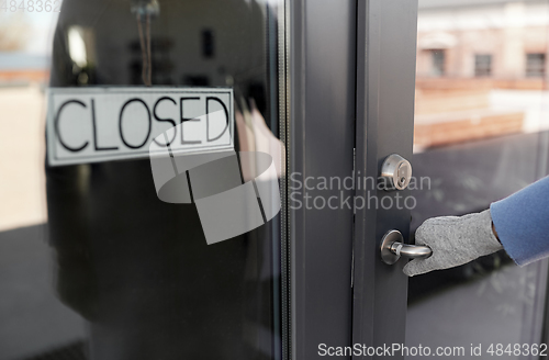 Image of hand in glove trying to open closed office door