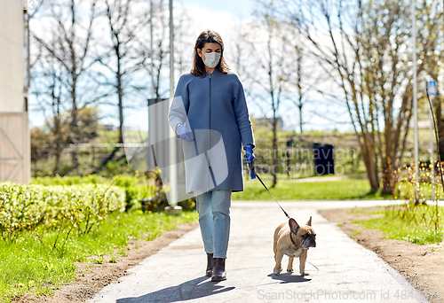 Image of woman in mask and gloves with dog walking in city