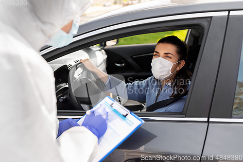 Image of healthcare worker with clipboard and woman in car