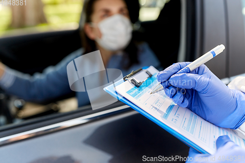 Image of healthcare worker with clipboard and woman in car