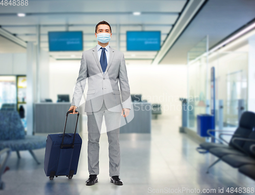 Image of businessman in mask with travel bag at airport