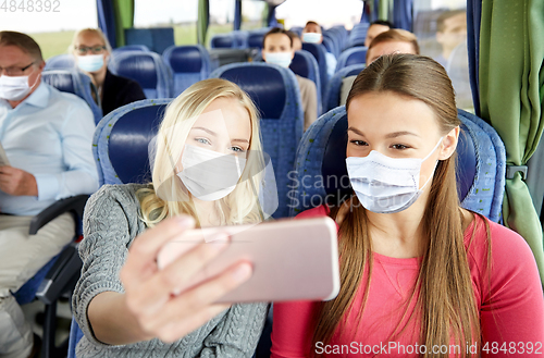 Image of women in medical masks taking selfie in travel bus