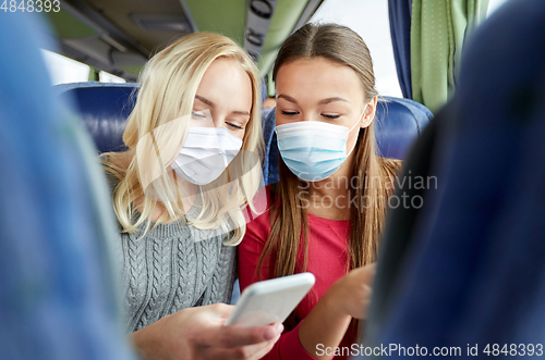 Image of women in masks in travel bus with smartphone