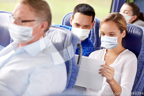 Image of couple in masks with tablet pc in travel bus