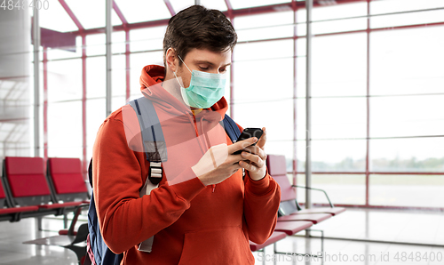 Image of man in mask with cellphone and backpack at airport