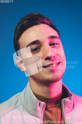 Image of Close up caucasian man\'s portrait isolated on blue studio background in neon light