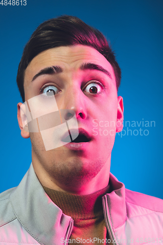 Image of Close up caucasian man\'s portrait isolated on blue studio background in neon light