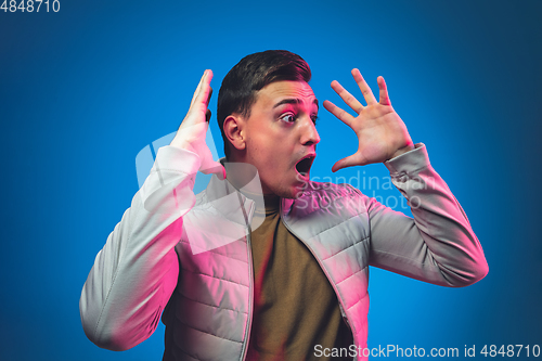 Image of Caucasian man\'s portrait isolated on blue studio background in neon light