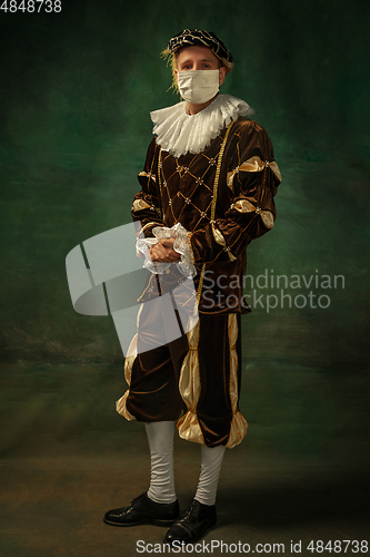 Image of Young man as a medieval knight on dark background wearing protective mask against coronavirus