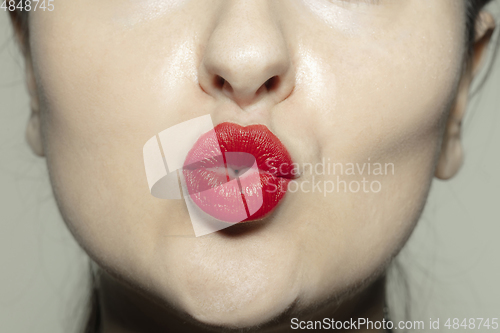 Image of Close-up female mouth with bright red gloss lips make-up. Cosmetology, dentistry and beauty care, emotions