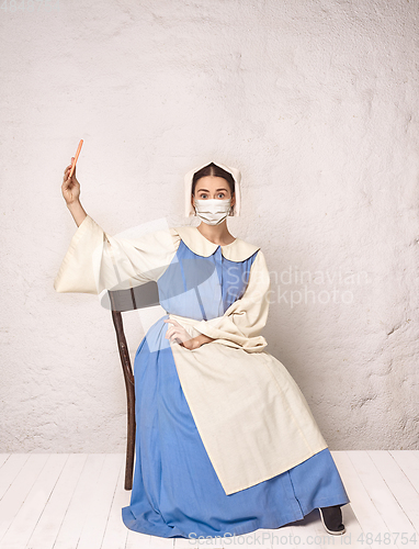 Image of Medieval young woman as a lady milkmade wearing protective mask against coronavirus spread