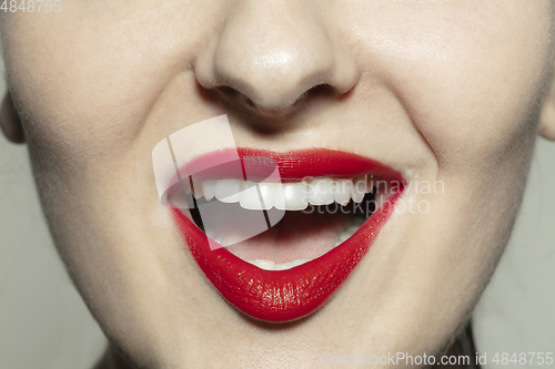 Image of Close-up female mouth with bright red gloss lips make-up. Cosmetology, dentistry and beauty care, emotions