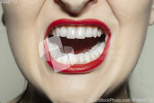 Image of Close-up female mouth with bright red gloss lips make-up. Cosmetology, dentistry and beauty care, emotions