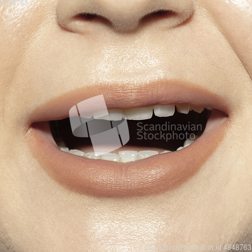Image of Close-up female mouth with natural nude gloss lips make-up. Cosmetology, dentistry and beauty care, emotions