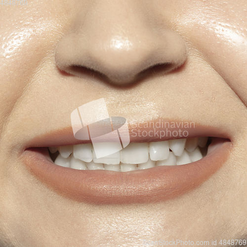 Image of Close-up female mouth with natural nude gloss lips make-up. Cosmetology, dentistry and beauty care, emotions