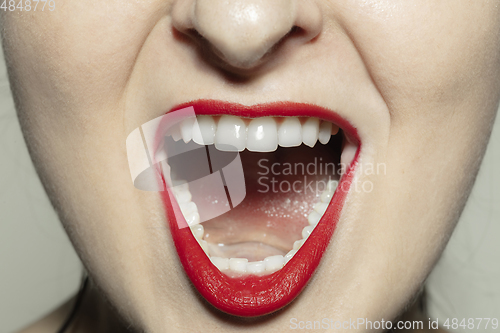 Image of Close-up female mouth with bright red gloss lips make-up. Cosmetology, dentistry and beauty care, emotions