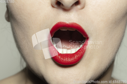 Image of Close-up female mouth with bright red gloss lips make-up. Cosmetology, dentistry and beauty care, emotions