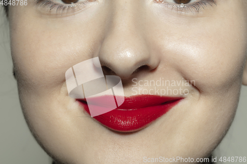 Image of Close-up female mouth with bright red gloss lips make-up. Cosmetology, dentistry and beauty care, emotions