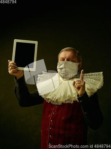 Image of Senior man as a medieval knight on dark background wearing protective mask against coronavirus