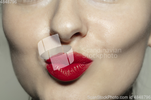 Image of Close-up female mouth with bright red gloss lips make-up. Cosmetology, dentistry and beauty care, emotions