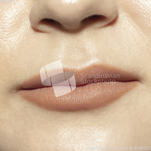 Image of Close-up female mouth with natural nude gloss lips make-up. Cosmetology, dentistry and beauty care, emotions