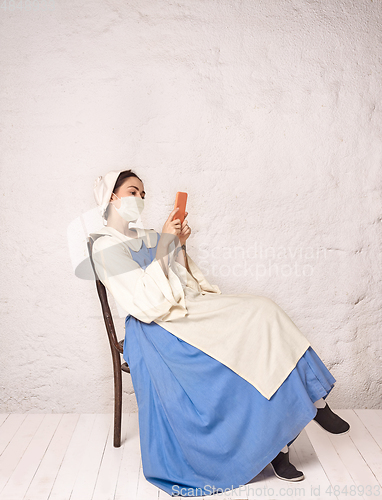 Image of Medieval young woman as a lady milkmade wearing protective mask against coronavirus spread