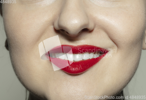 Image of Close-up female mouth with bright red gloss lips make-up. Cosmetology, dentistry and beauty care, emotions
