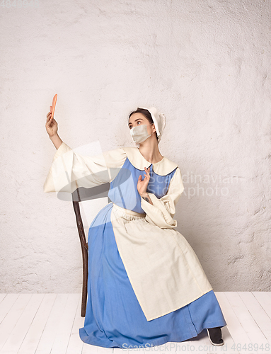 Image of Medieval young woman as a lady milkmade wearing protective mask against coronavirus spread