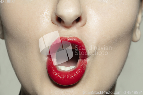 Image of Close-up female mouth with bright red gloss lips make-up. Cosmetology, dentistry and beauty care, emotions