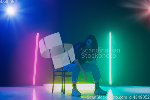 Image of Young caucasian girl posing stylish in neon light on dark background