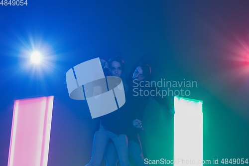 Image of Cheering dance party, performance concept. Couple dancing with neon lights raised hands up