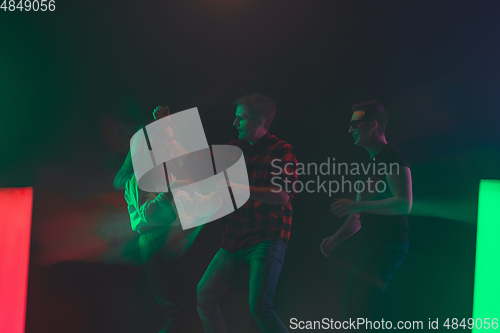 Image of Cheering dance party, performance concept. Crowd shadow of people dancing with neon lights raised hands up