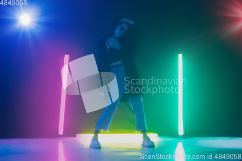 Image of Young caucasian girl posing stylish in neon light on dark background