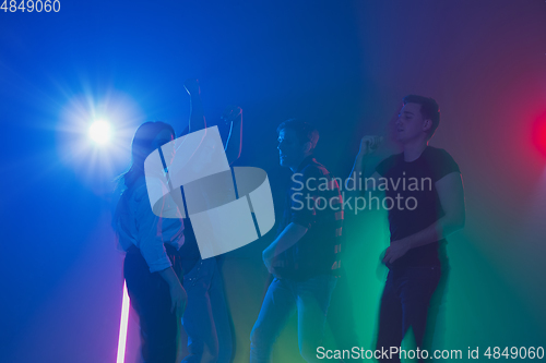 Image of Cheering dance party, performance concept. Crowd shadow of people dancing with neon lights raised hands up