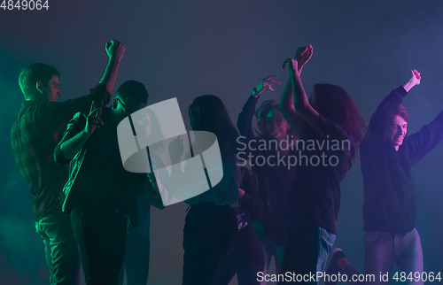 Image of Cheering dance party, performance concept. Crowd shadow of people dancing with neon lights raised hands up