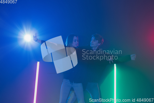 Image of Cheering dance party, performance concept. Couple dancing with neon lights raised hands up