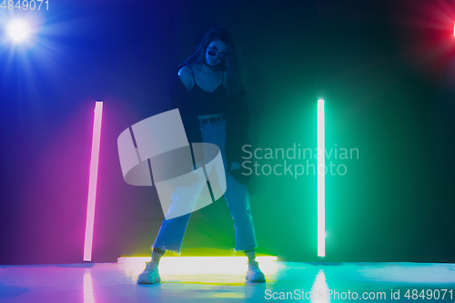 Image of Young caucasian girl posing stylish in neon light on dark background