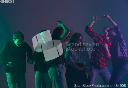 Image of Cheering dance party, performance concept. Crowd shadow of people dancing with neon lights raised hands up