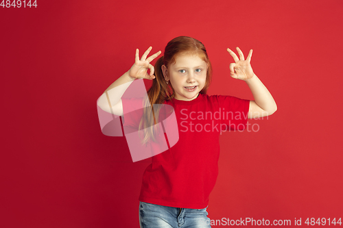 Image of Caucasian little girl portrait isolated on red studio background, emotions concept