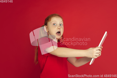 Image of Caucasian little girl portrait isolated on red studio background, emotions concept