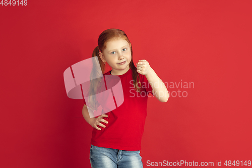 Image of Caucasian little girl portrait isolated on red studio background, emotions concept