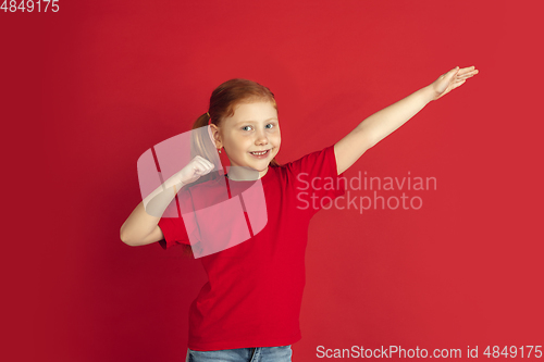 Image of Caucasian little girl portrait isolated on red studio background, emotions concept