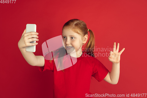 Image of Caucasian little girl portrait isolated on red studio background, emotions concept